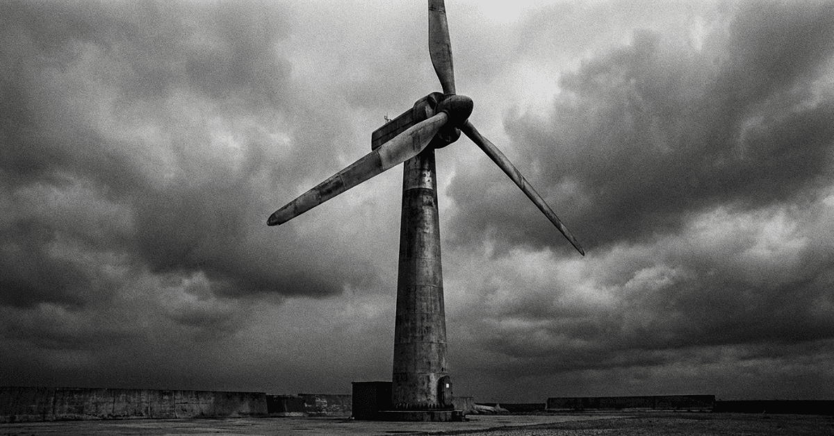 Wind turbine holding steady beneath storm clouds.